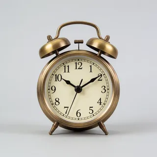 Reference 8: a vintage brass alarm clock on a plain grey background